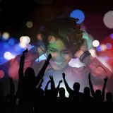 Uśmiechnięta dziewczyna w słuchawkach, otoczona tańczącym tłumem. Czy warto było szaleć tak? Światła dyskoteki tworzą magiczną atmosferę.