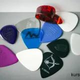 Różnorodne kostki do gry na gitarze, w tym jedna z motywem łuku i strzały, gotowe do tworzenia muzyki.