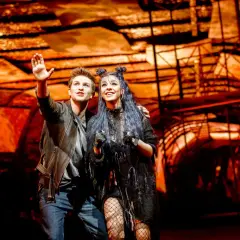Para z musicalu "We Will Rock You" w polskim tłumaczeniu, pozdrawia publiczność na tle scenografii.