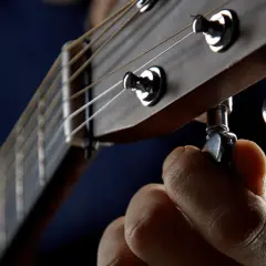 Dłoń kręci kluczem, by drop a tuning na gitarze. Idealne brzmienie jest blisko.