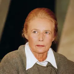 Portret kobiety z rudymi włosami, w szarym swetrze i białej koszuli. Jej spojrzenie sugeruje głęboką refleksję, jakby słyszała "uciekaj moje serce interpretacja".