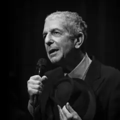 Leonard Cohen, z mikrofonem i kapeluszem w dłoni, śpiewa swoje ponadczasowe utwory.