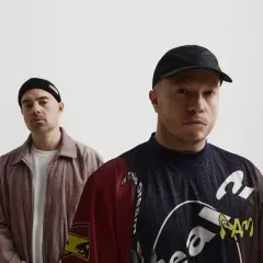 Dwóch mężczyzn, jeden w czapce beanie, drugi w czapce z daszkiem, pozuje do zdjęcia. To okładka jednego z pro8l3m albumy.