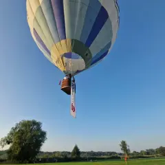Balon z koszem i banerem unosi się na błękitnym niebie. Może to symbolizować wolność, jak w piosence "99 luftballons znaczenie".