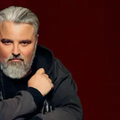 Mirosław Niewiadomski, z siwą brodą i włosami, w bluzie z kapturem. Jego życiorys to historia pasji i determinacji.
