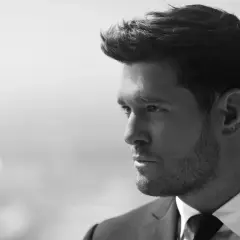 Michael Bublé w garniturze, zamyślony. Jego ponadczasowe michael bublé utwory brzmią jak jego spojrzenie.