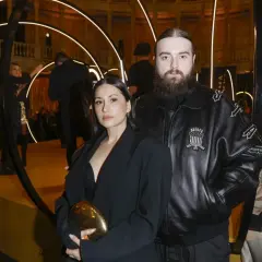 Bedoes z partnerką, która wygląda jakby była w ciąży, na złotej scenie z okręgami świetlnymi.