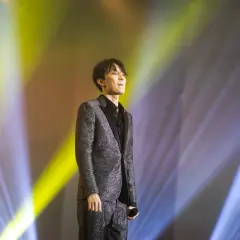 Dimash Kudaibergen w błyszczącym garniturze na scenie, w świetle reflektorów. Jego życie prywatne pozostaje tajemnicą.