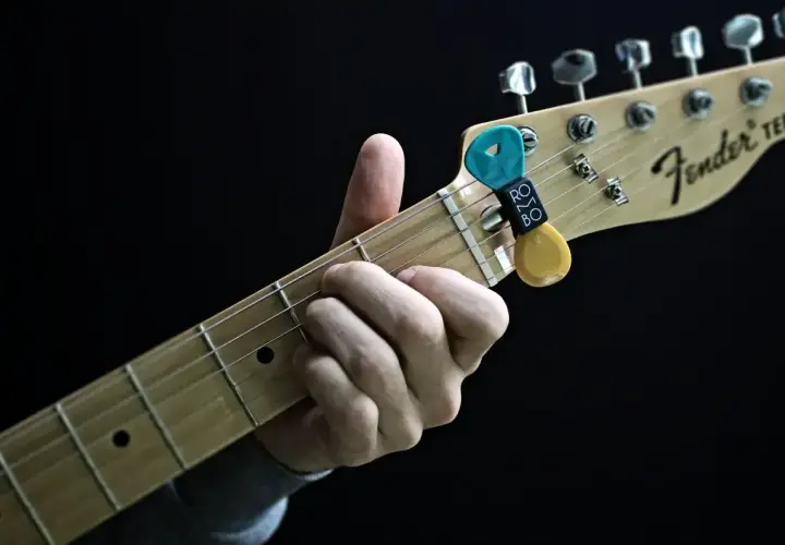 Dłoń grająca akord na gryfie gitary Fender Telecaster. Kostka z uchwytem na gryfie.