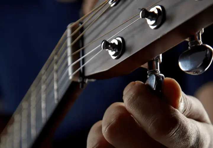 Dłoń kręci kluczem, by drop a tuning na gitarze. Idealne brzmienie jest blisko.