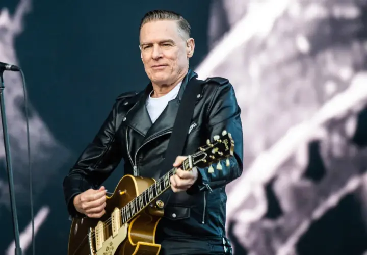 Bryan Adams w skórzanej kurtce gra na gitarze, przypominając klimat lata '69.