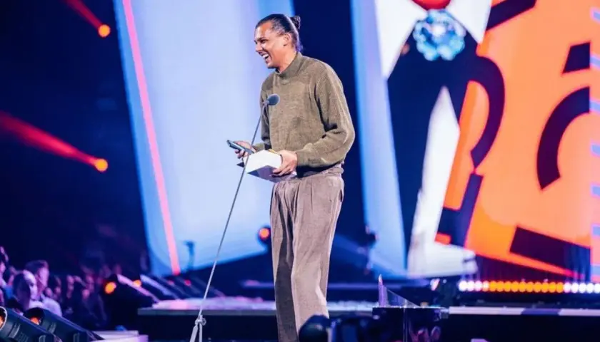Stromae z nagrodą na scenie, jakby śpiewał "Papaoutai tekst po polsku".