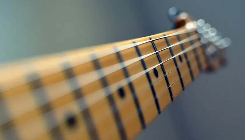 Zbliżenie na gryf gitary elektrycznej. Zastanawiasz się, ile trwa nauka gry na gitarze? To zależy od Ciebie!