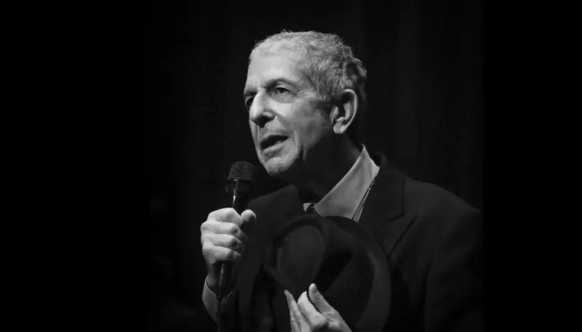 Leonard Cohen, z mikrofonem i kapeluszem w dłoni, śpiewa swoje ponadczasowe utwory.