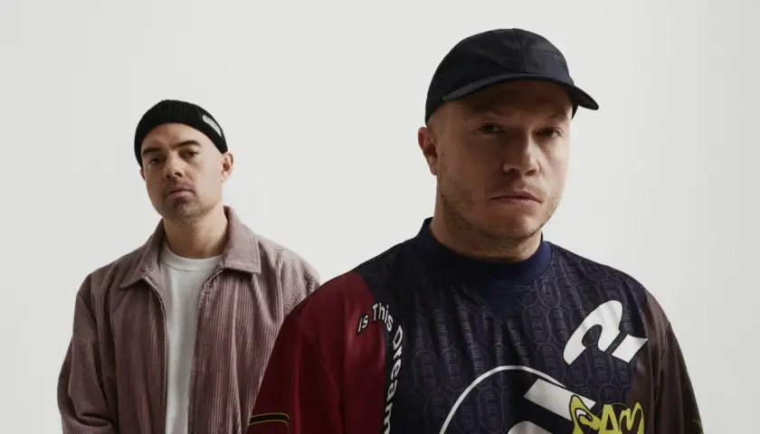 Dwóch mężczyzn, jeden w czapce beanie, drugi w czapce z daszkiem, pozuje do zdjęcia. To okładka jednego z pro8l3m albumy.