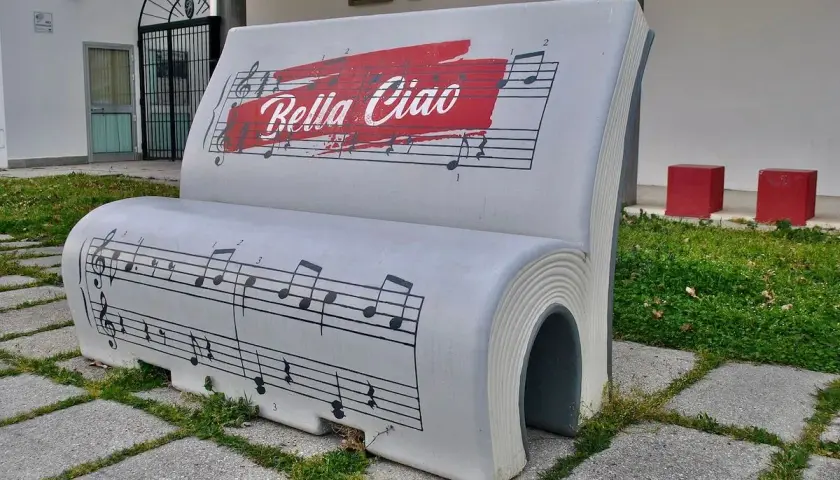 Ławka w kształcie książki z nutami i napisem "Bella Ciao tekst".