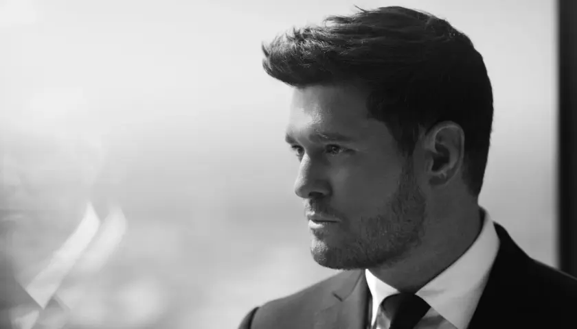 Michael Bublé w garniturze, zamyślony. Jego ponadczasowe michael bublé utwory brzmią jak jego spojrzenie.