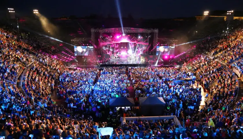 Koncert włoskich piosenkarzy na wypełnionym po brzegi stadionie. Tłum w euforii, światła sceny i ekranów tworzą magiczną atmosferę.