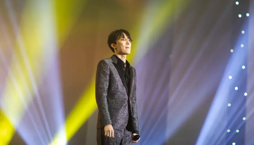 Dimash Kudaibergen w błyszczącym garniturze na scenie, w świetle reflektorów. Jego życie prywatne pozostaje tajemnicą.