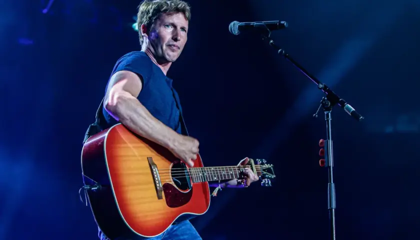 James Blunt na koncercie, grając na gitarze. W tle mikrofon, przypominający o jego hicie "You're Beautiful".