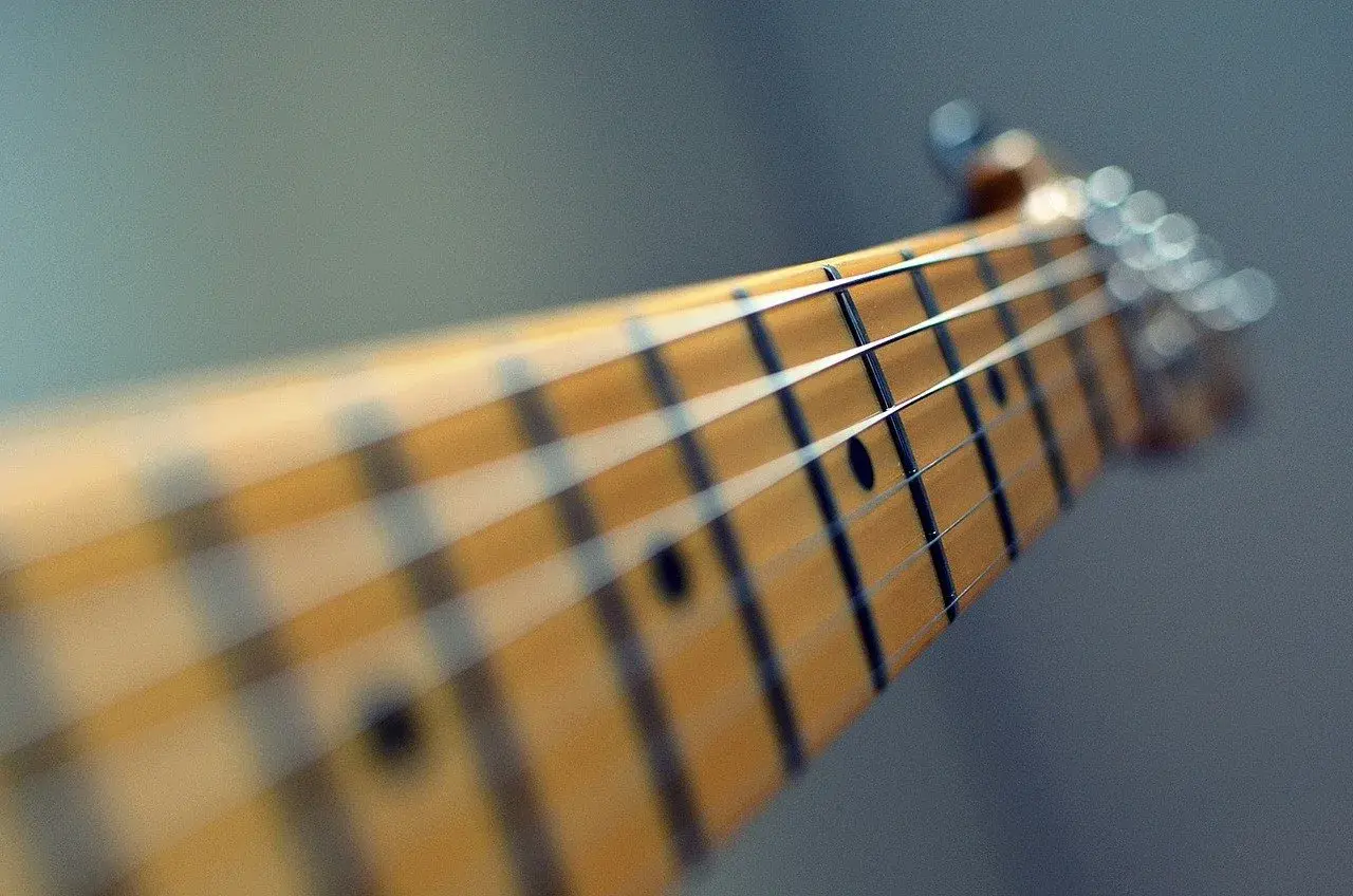 Zbliżenie na gryf gitary elektrycznej. Zastanawiasz się, ile trwa nauka gry na gitarze? To zależy od Ciebie!