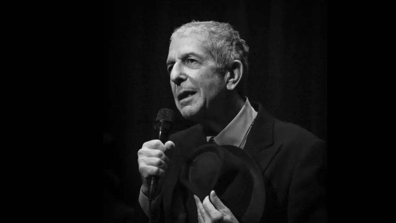 Leonard Cohen, z mikrofonem i kapeluszem w dłoni, śpiewa swoje ponadczasowe utwory.