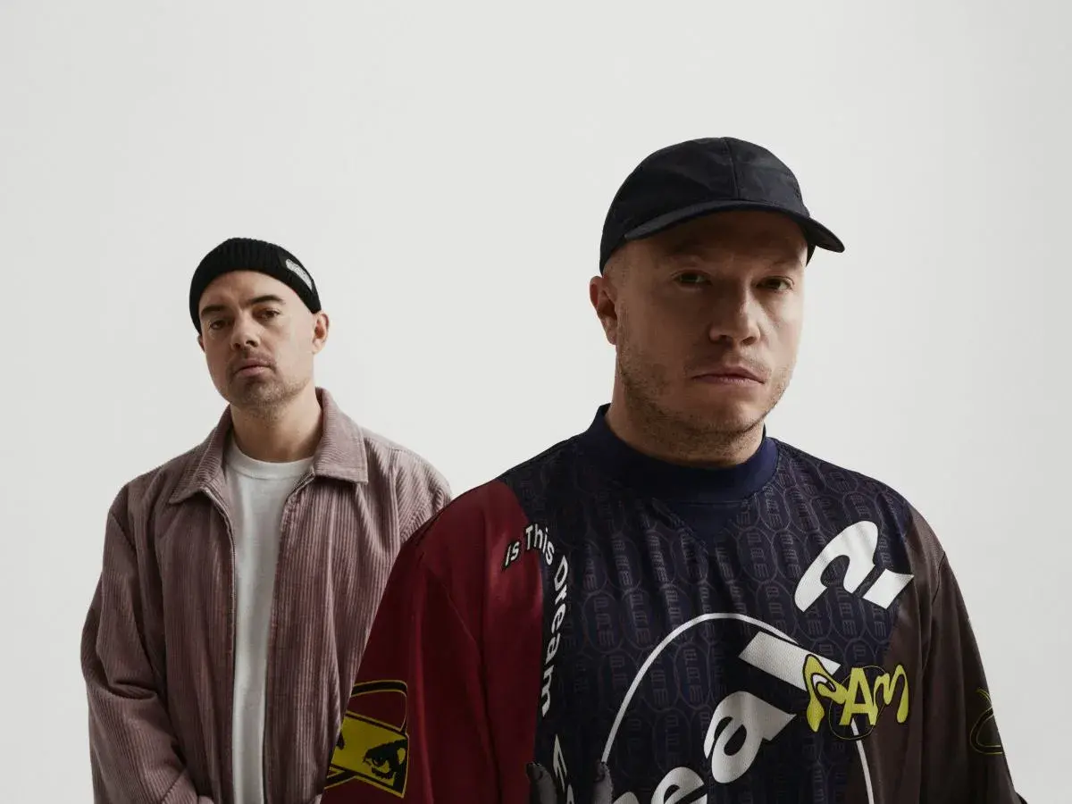 Dwóch mężczyzn, jeden w czapce beanie, drugi w czapce z daszkiem, pozuje do zdjęcia. To okładka jednego z pro8l3m albumy.