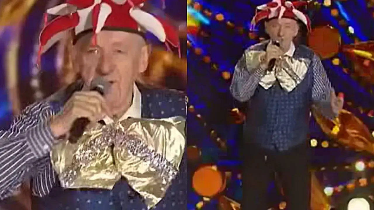 Artysta w stroju błazna śpiewa na scenie. Może to być fragment koncertu z piosenkami Rosiewicza alfabetycznie.