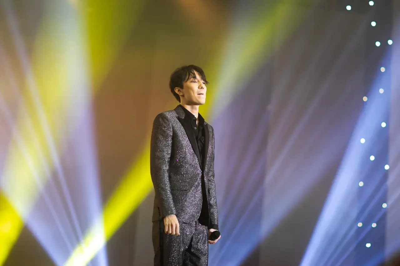 Dimash Kudaibergen w błyszczącym garniturze na scenie, w świetle reflektorów. Jego życie prywatne pozostaje tajemnicą.