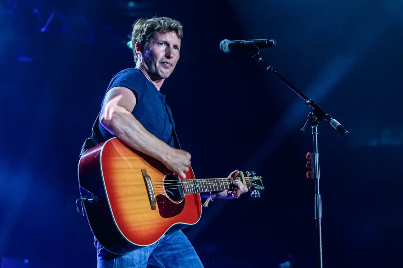 James Blunt na koncercie, grając na gitarze. W tle mikrofon, przypominający o jego hicie "You're Beautiful".