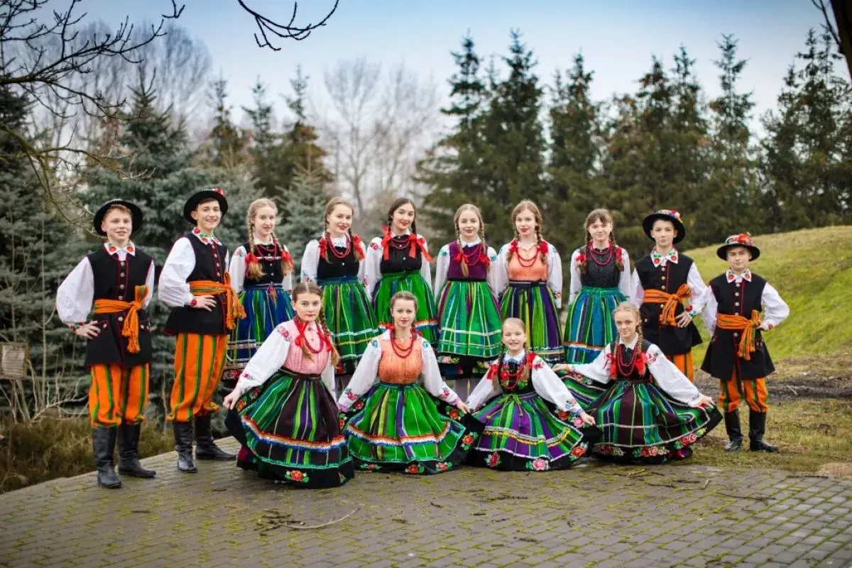 Dzieci w barwnych strojach ludowych, gotowe do wykonania znanych piosenek ludowych.