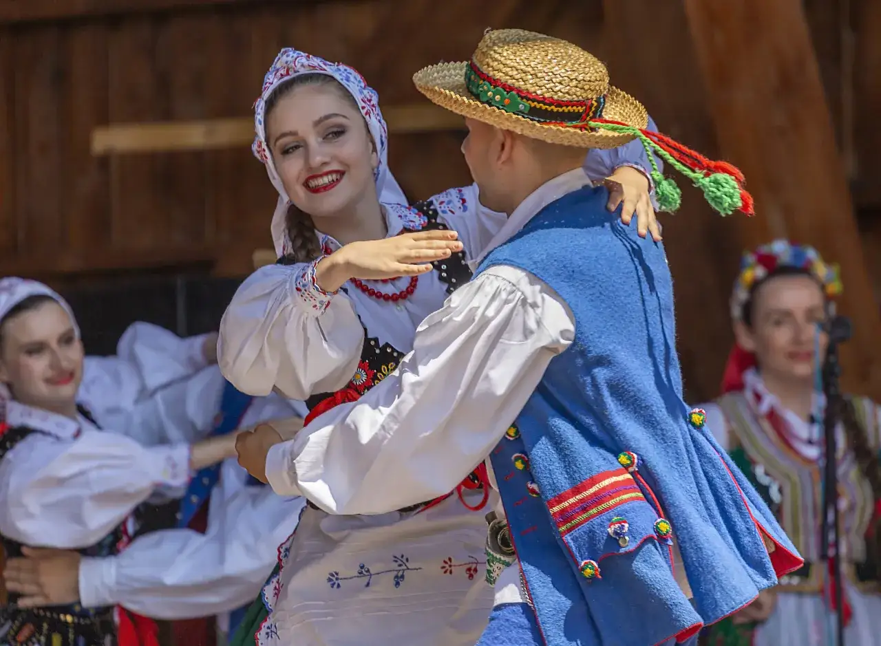 Para tańczy w tradycyjnych strojach do skocznych piosenek ludowych.