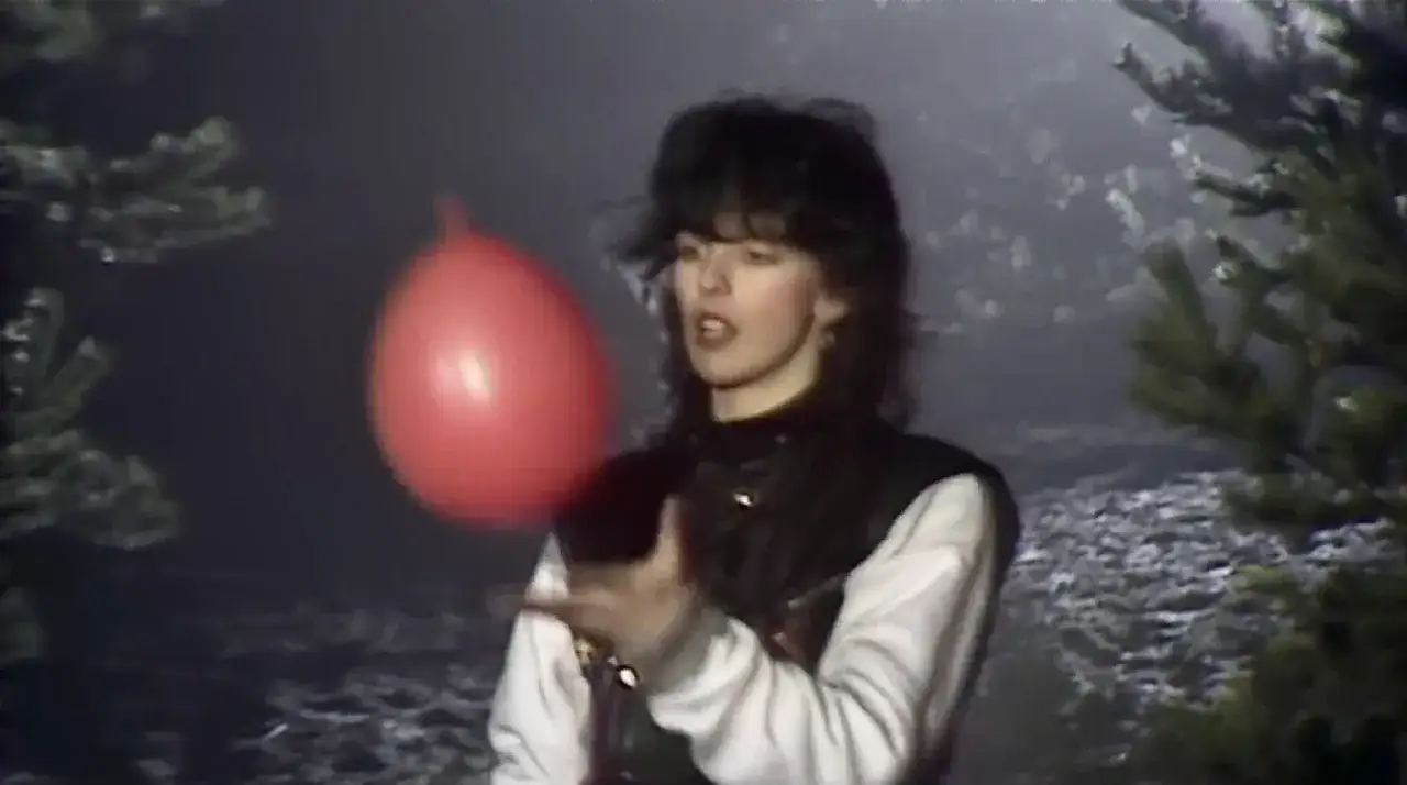 Kobieta z burzą włosów trzyma czerwony balon, jak w teledysku