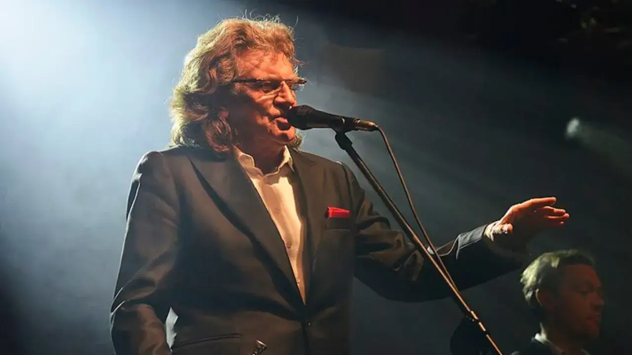 Charyzmatyczny wokalista, jeden z legendarnych polskich piosenkarzy lat 70 i 80, śpiewa do mikrofonu na scenie.