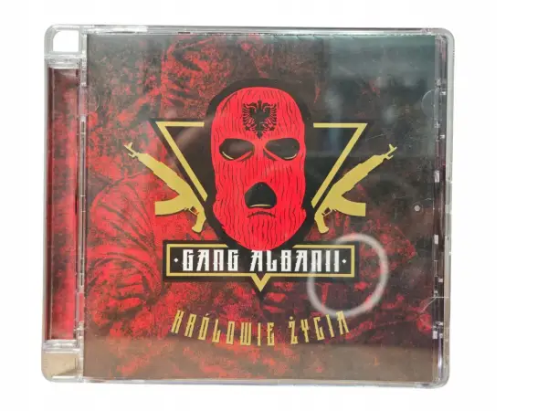 Okładka płyty CD "Królowie życia" zespołu Gang Albanii. Czerwona kominiarka z orłem, złote kałasznikowy i mroczne tło.